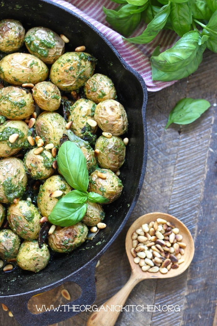 Roasted Baby Potatoes with Pesto: Traditional and Whole30, dairy free, vegan option in black skillet with a spoon full of pine nuts