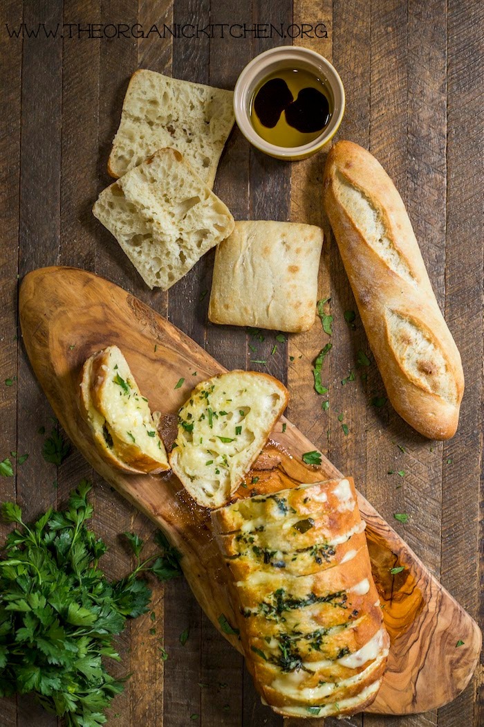 Cheesy Bread with Herbed Butter on a wooden table with a small bowl of dipping oil and balsamic vinegar