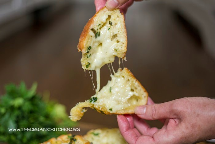 A woman's hands separating Cheesy Bread with Herbed Butter!