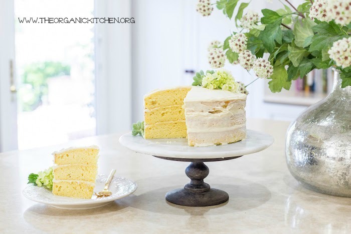 Buttermilk Cake with Vanilla Bean Cream Cheese Frosting on a cake plate with a slice of cake on a small dish