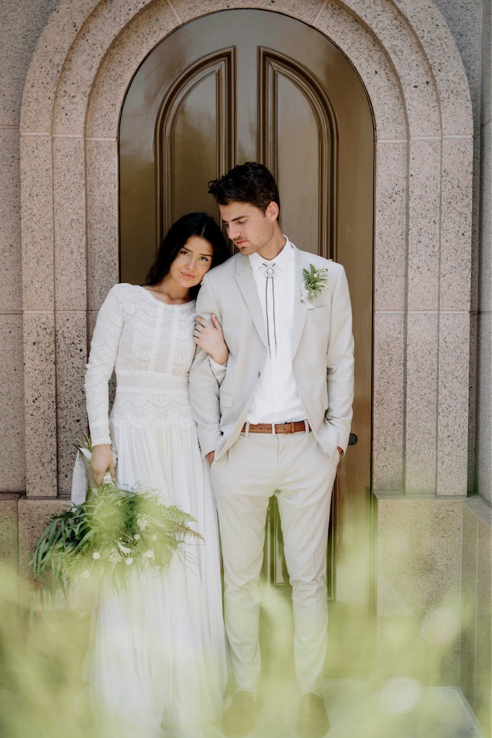 A bride and groom standing arm in arm under an arch