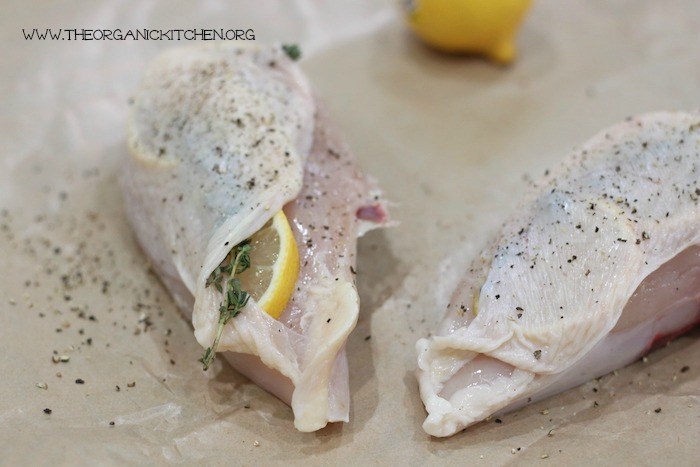 Raw chicken breasts stuffed with lemon slices and thyme in preparation to make Paleo Roast Lemon Chicken with Maple Cauliflower Purée with a Whole 30 Option