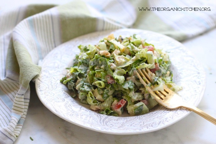 A chopped chicken salad with ranch in white bowl with gold fork.