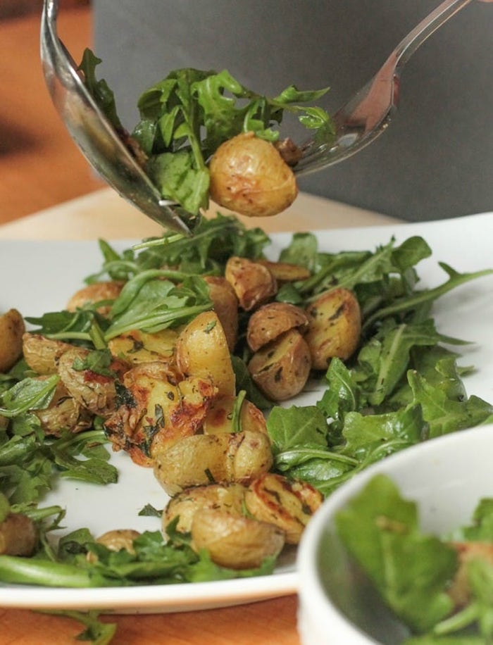 Roasted potato and arugula salad on white plate. 12 Healthy Whole30 Vegetable Side Dishes!