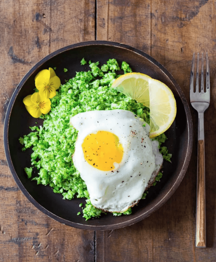 Broccoli rice and fried egg in black bowl as part of 12 Healthy Whole30 Vegetable Side Dishes!