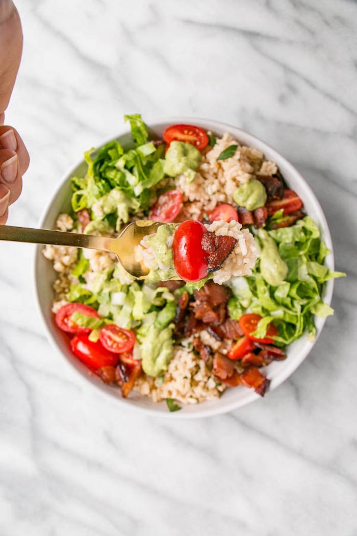 A white bowl filled with vegetables, rice, bacon and avocado as part of 12 Fantastic Rice Bowl Recipes!