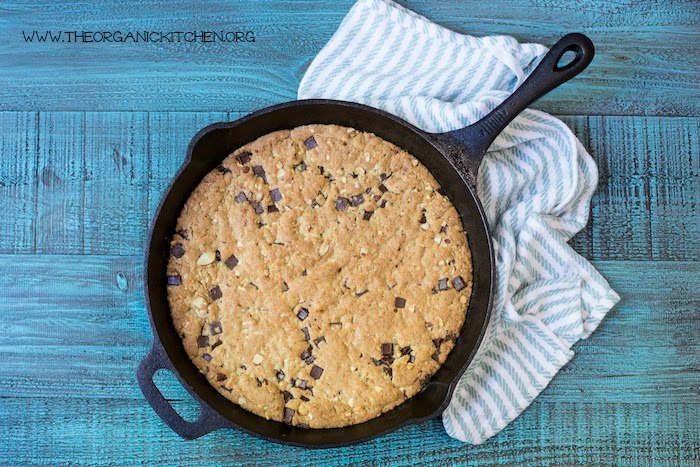 'Almond Joy' Chocolate Chip Skillet Cookie! (Gluten free option) in a black skillet with blue and white dish towel underneath