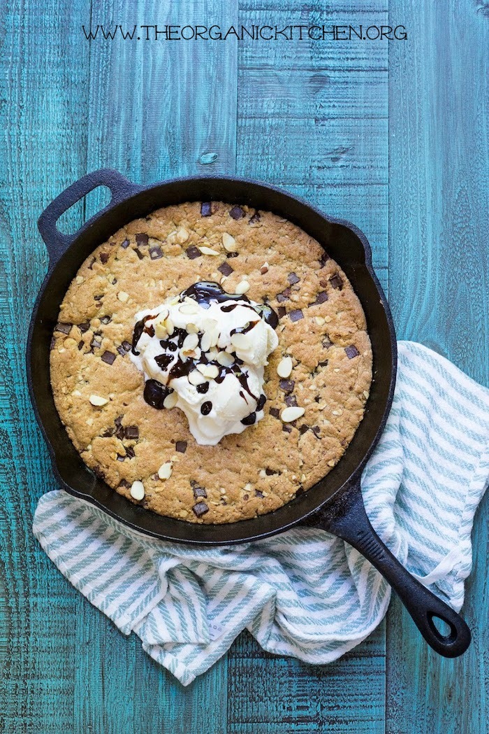 'Almond Joy' Chocolate Chip Skillet Cookie! (Gluten free option) topped with vanilla ice cream and hot fudge with blue and white dish towel underneath