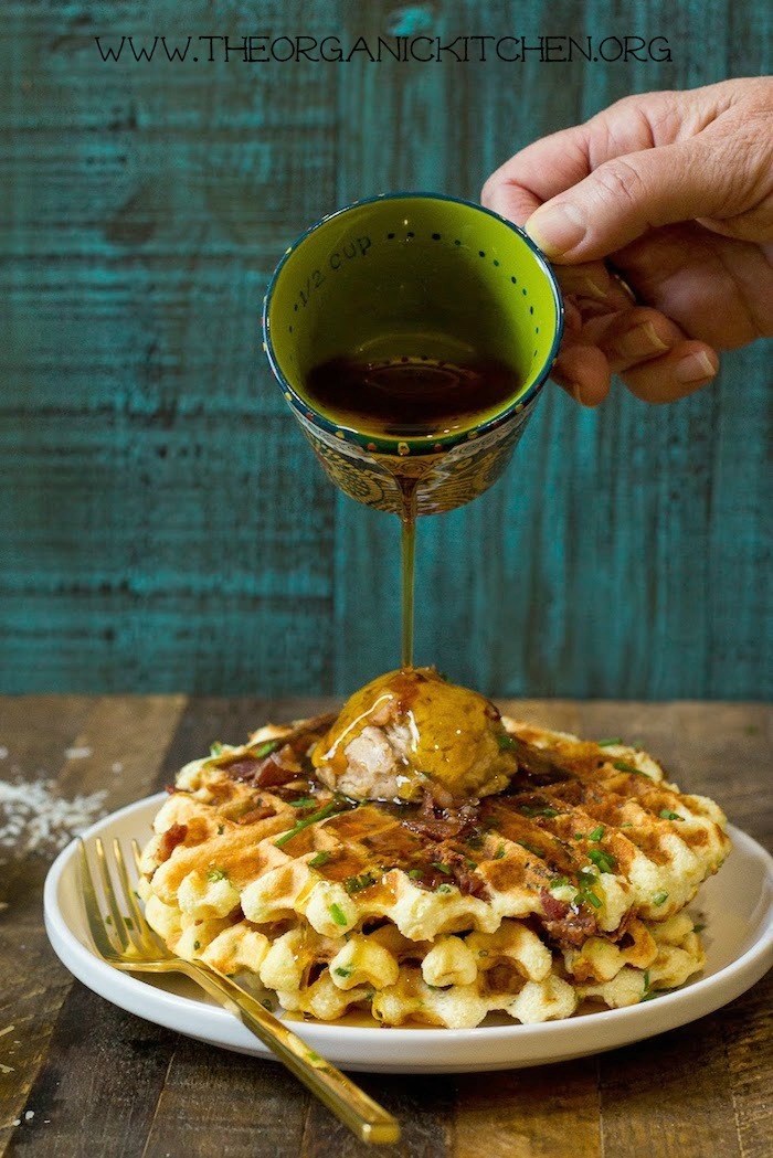 Parmesan Chive Jalapeño Waffles with Maple Cinnamon Butter on a plate being drizzled with syrup