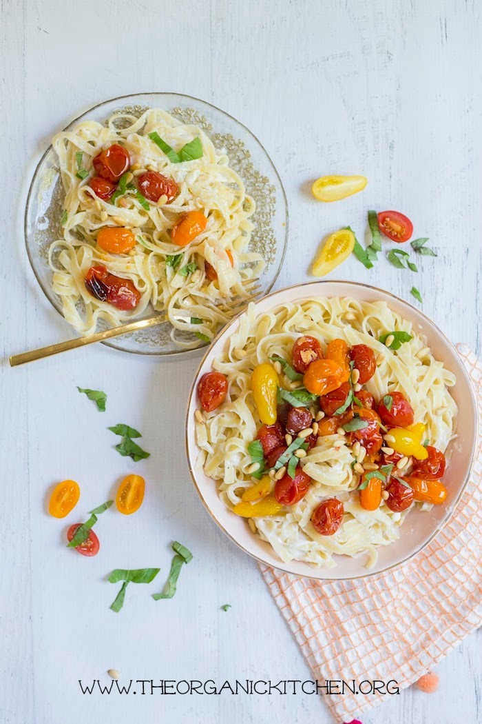 A bowl and plate overflowing with Pasta with Blistered Tomatoes and Ricotta on a white background