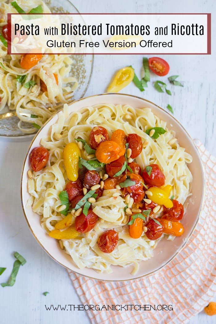 Pasta with Blistered Tomatoes and Ricotta in a coral colored bowl on a white backdrop