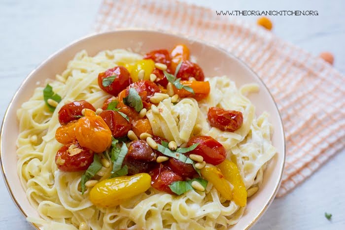 A close up og Pasta with Blistered Tomatoes and Ricotta in light orange bowl with orange and white dish towel