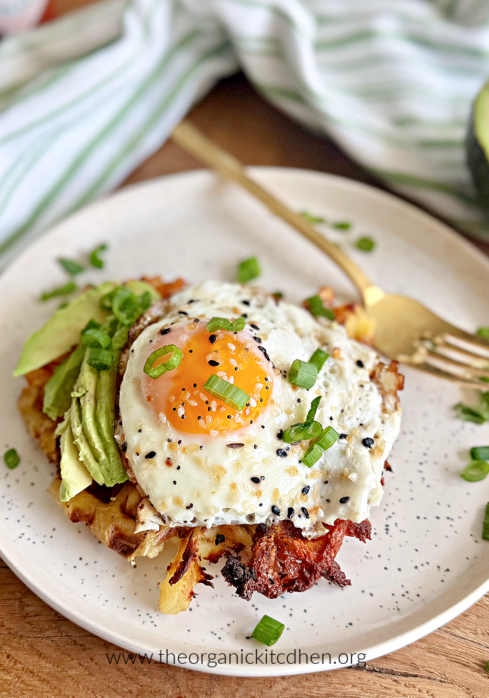12 Beautiful and Unique Waffle Recipes Parmesan Potato Waffle topped with fried egg, avocado and chives on white plate
