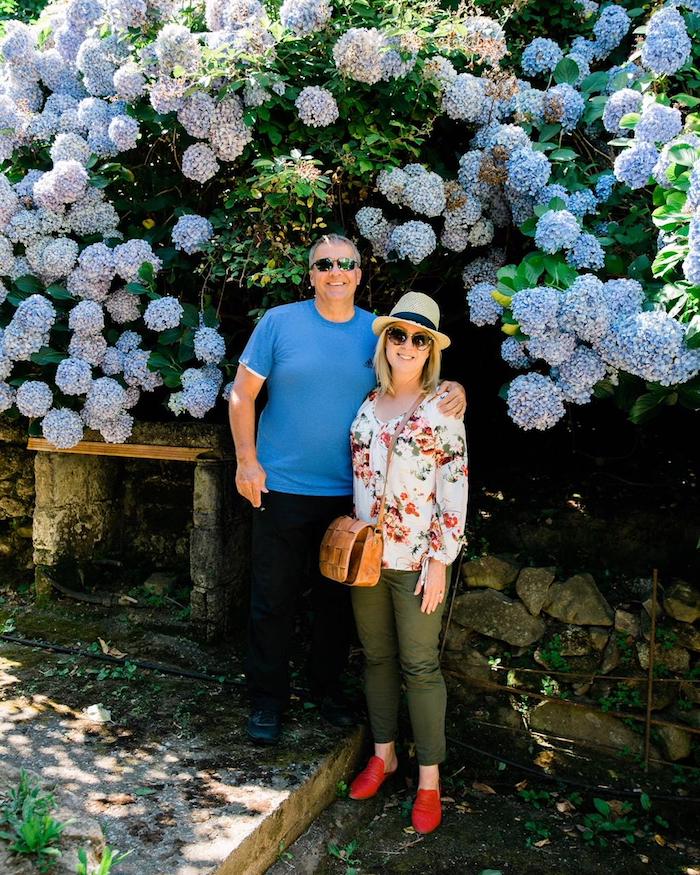 A couple standing in front of huge hydrangea bushes with periwinkle blue flowers  on the Island of Capri