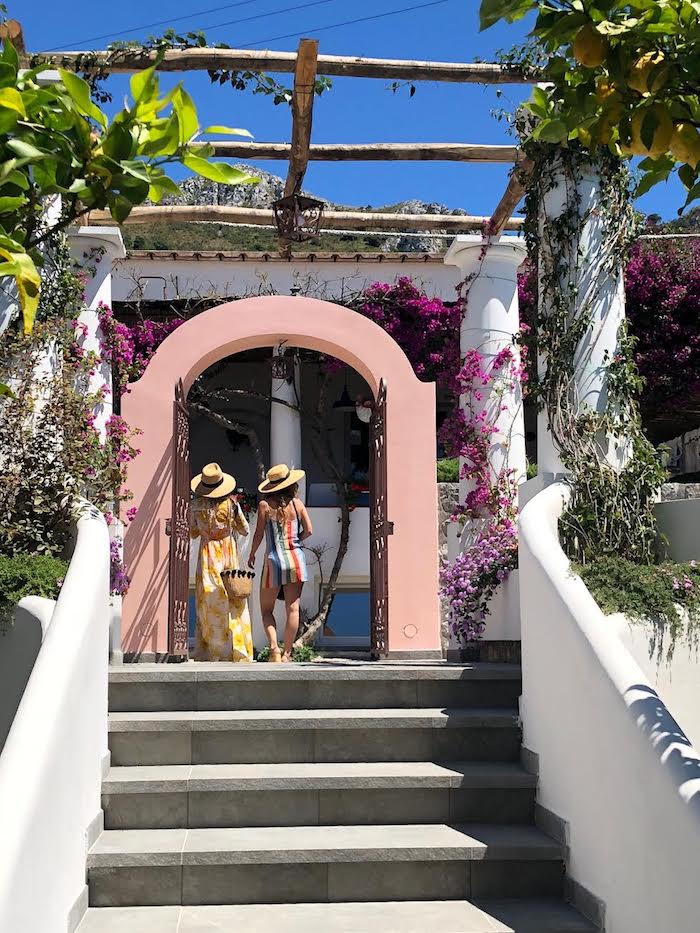 Two women in  hats and dresses under an arch on the Island of Capri