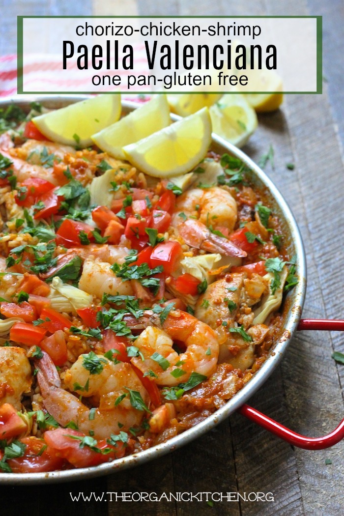 Paella Valenciana with Chicken, Chorizo and Shrimp garnished with lemon wedges in a paella pan