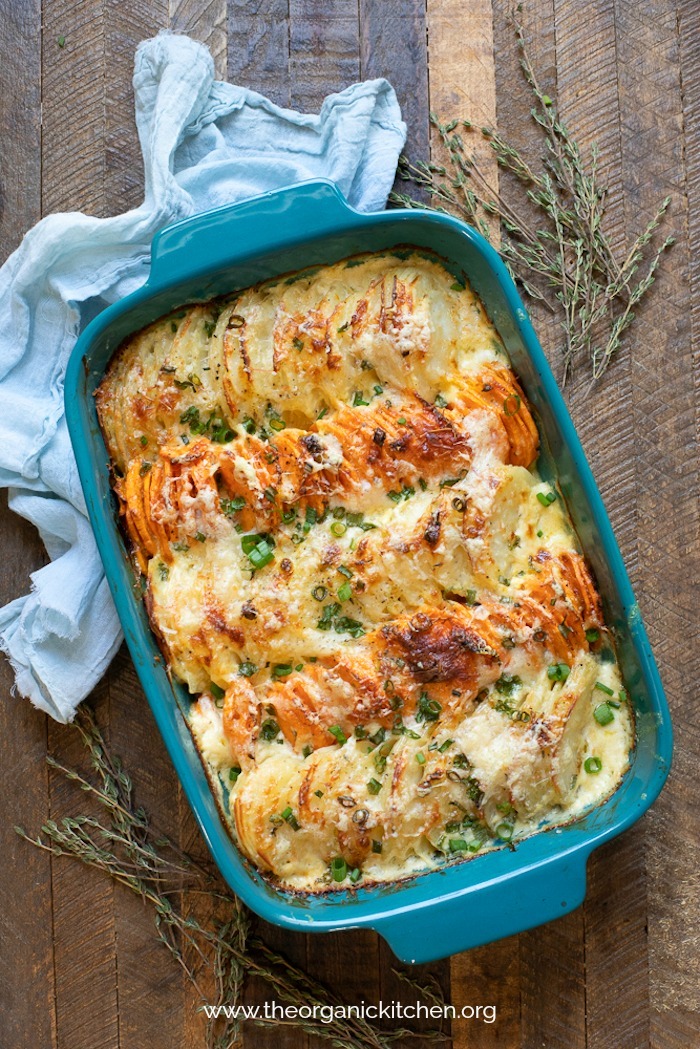 Orange and White Easy Potato Gratin in teal baking dish with blue cloth draped on table