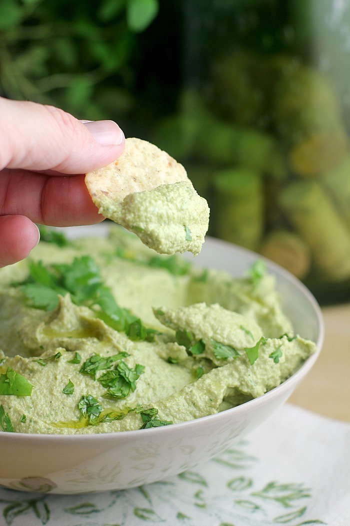 Fingers dipping a cracker into a gree dip as part of 20+ Whole30 Dips, Sauces and Salad Dressings! 