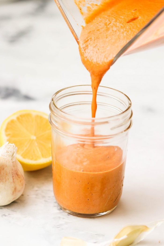 Red bell pepper sauce being poured into a jar as part of 20+ Whole30 Dips, Sauces and Salad Dressings! 