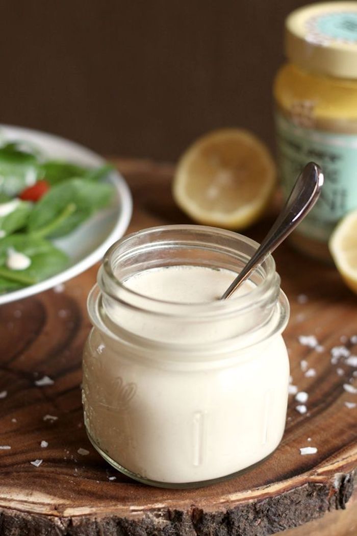 Lemon Tahini dressing in a small jar with salad in the background as part of 20+ Whole30 Dips, Sauces and Salad Dressings!