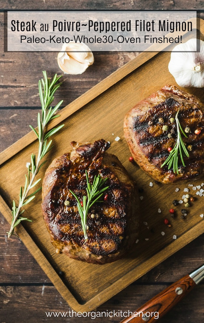 Steak Au Poivre (Peppered Filet Mignon) garnished with rosemary on a wood cutting board