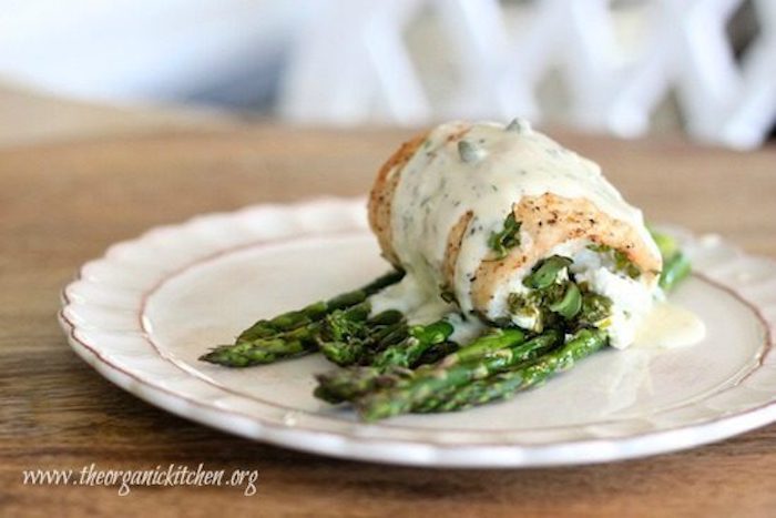 Spinach and Goat Cheese Stuffed Chicken Breasts on Asparagus with Dill Cream Sauce garnished with capers