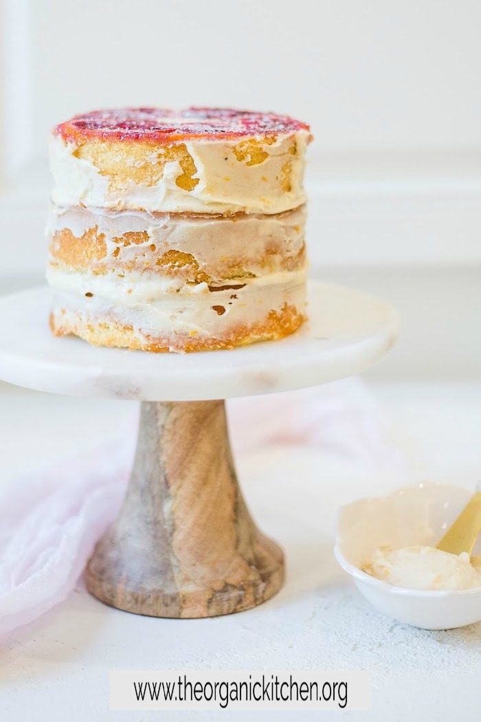 Triple Layer Orange Upside Down Cake on white marble cake plate with pink fabice in background