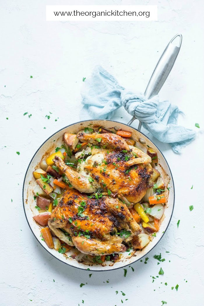 Two Cornish Game Hens in a pan with roasted vegetables