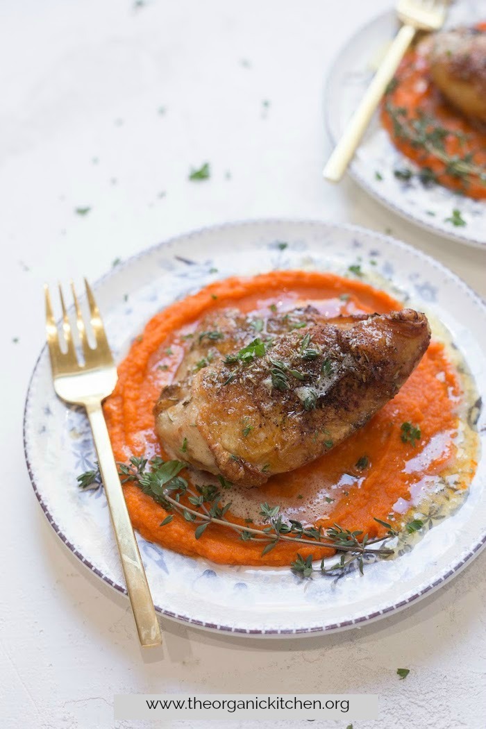 A plate Herbed Chicken Breast with Carrot Purée and Brown Butter on white and blue plate with gold fork