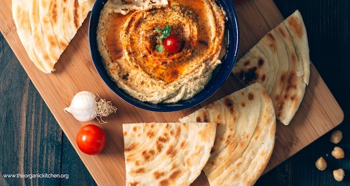 Sun dried tomato hummus in a blue bowl on wood platter