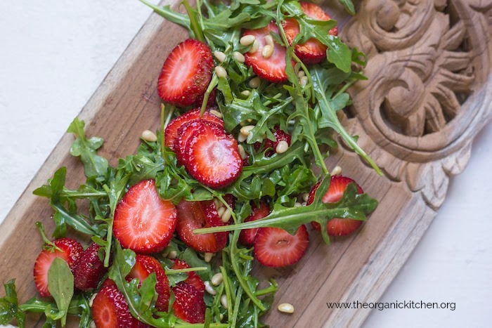 Grilled Chicken with Strawberry and Arugula Salad on wooden cutting board set on white background