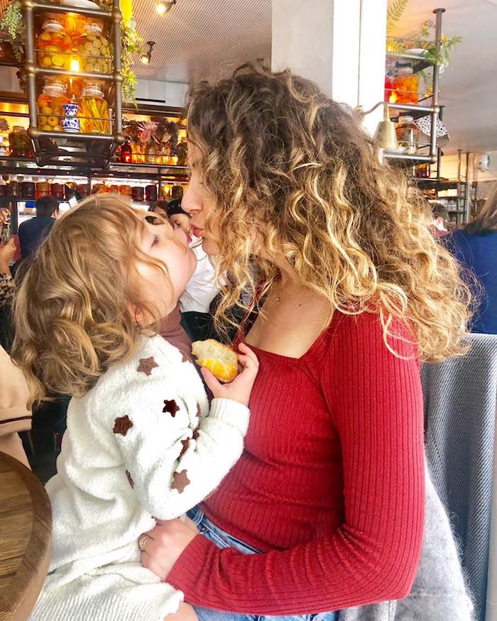 A mother and baby kissing while sititng in a restaurant 