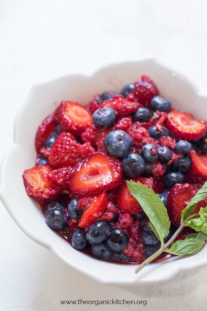 Macerated Berries and Sour Whipped Cream garnished with mint in a pretty white bowl 