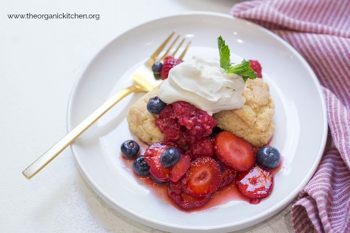 Macerated Berries and Sour Whipped Cream served with a scone on a white plate with gold fork