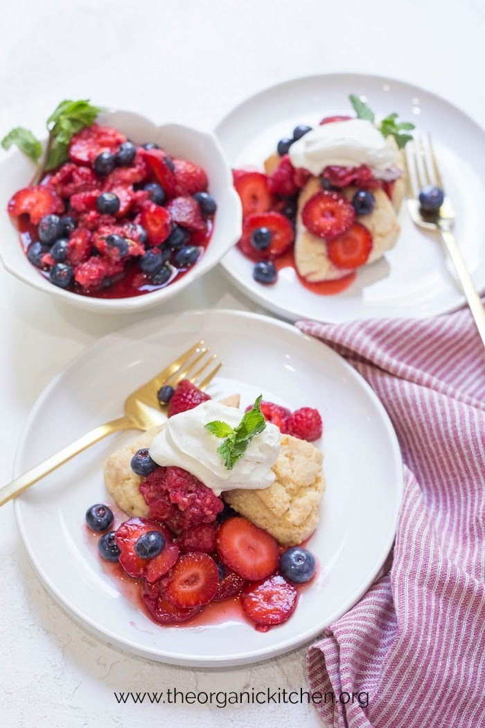 Macerated Berries and Sour Whipped Cream with a red and white dish towel and gold forks