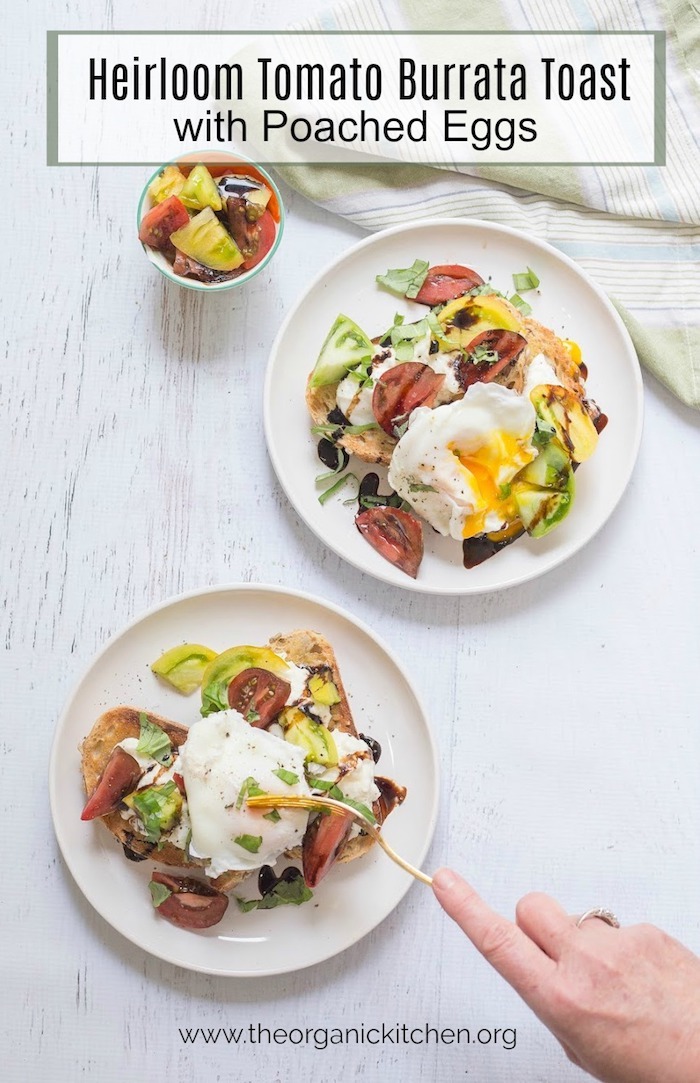 A woman's hand using a fork to cut into Heirloom Tomato Burrata Toast with Poached Eggs