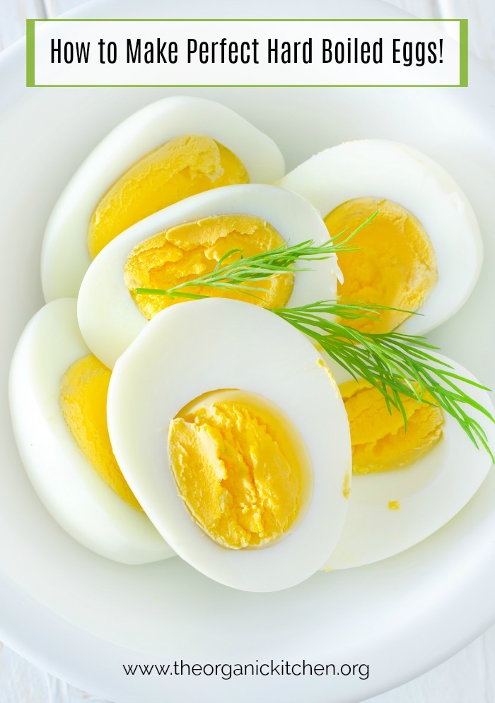 How to Make Perfect Hard Boiled Eggs: Hard boiled eggs, cut in half, in white bowl, garnished with herbs