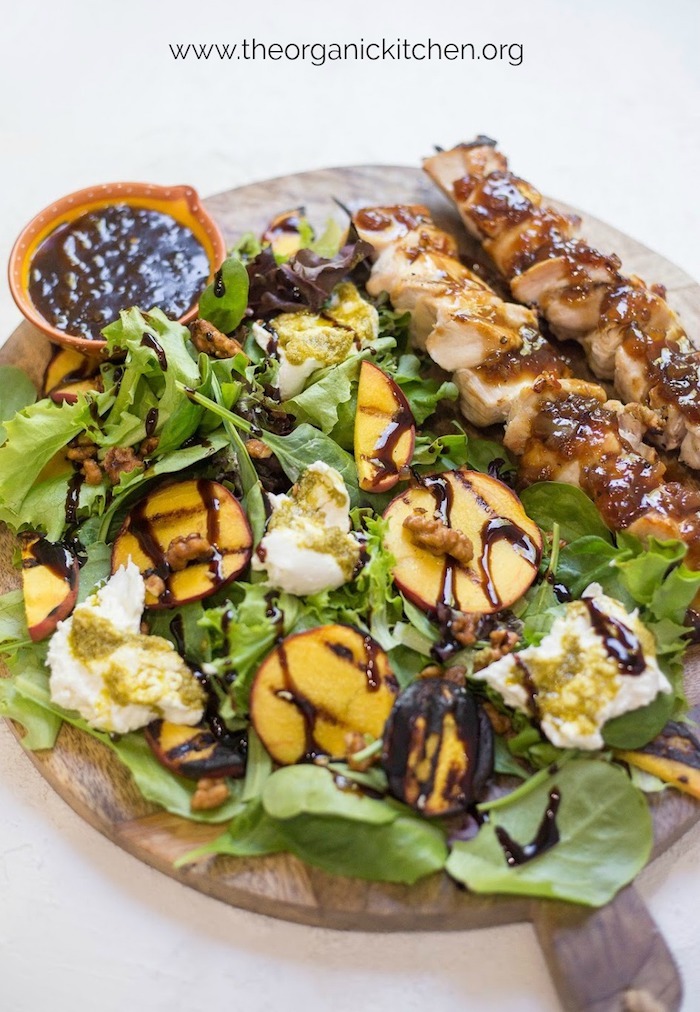 Grilled Peach and Burrata Salad with chicken skewers on a wooden platter