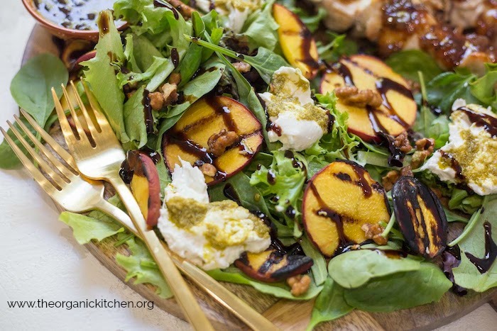 Grilled Peach and Burrata Salad with two gold forks on a round serving board