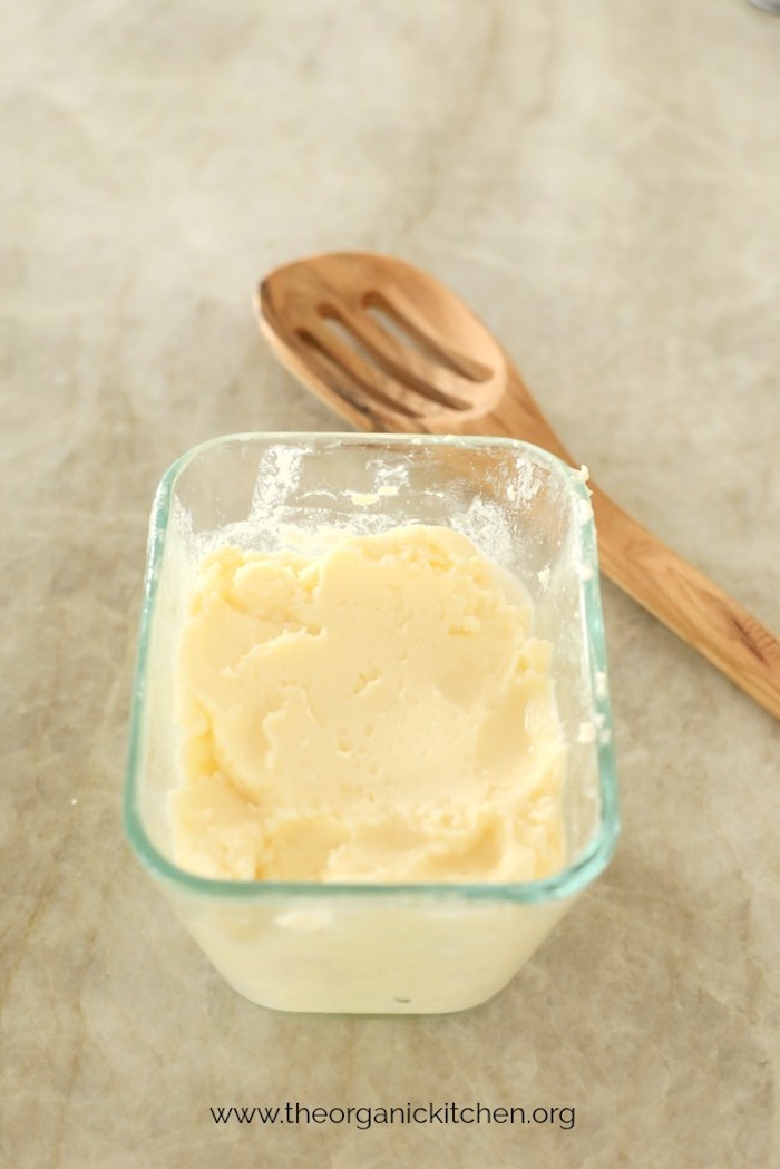 How to Make Raw or Pasteurized Butter: butter in a small dish with wooden spoon in background