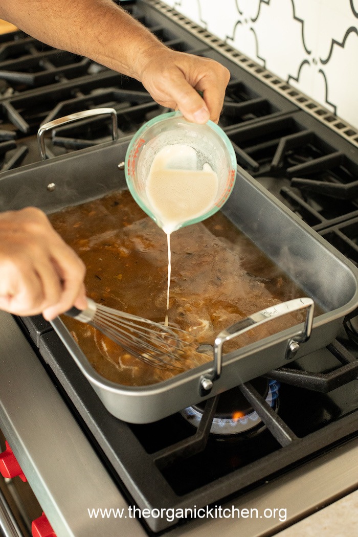 A man holding using a  whisk demonstrating How to Make Turkey Gravy with Drippings 