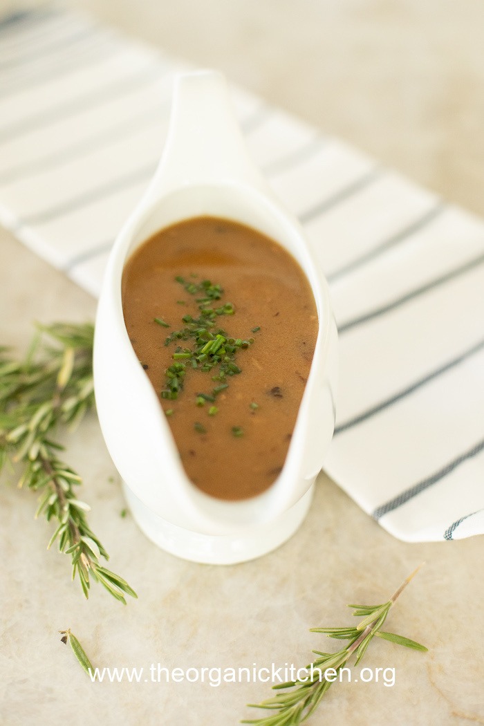 A white gravy boat filled with rich brown gravy to be used on Classic Easy Mashed Potatoes