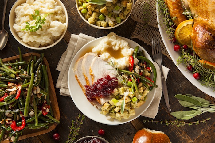 A white plate filled with Thanksgiving food with a big bowl of Classic Easy Mashed Potatoes