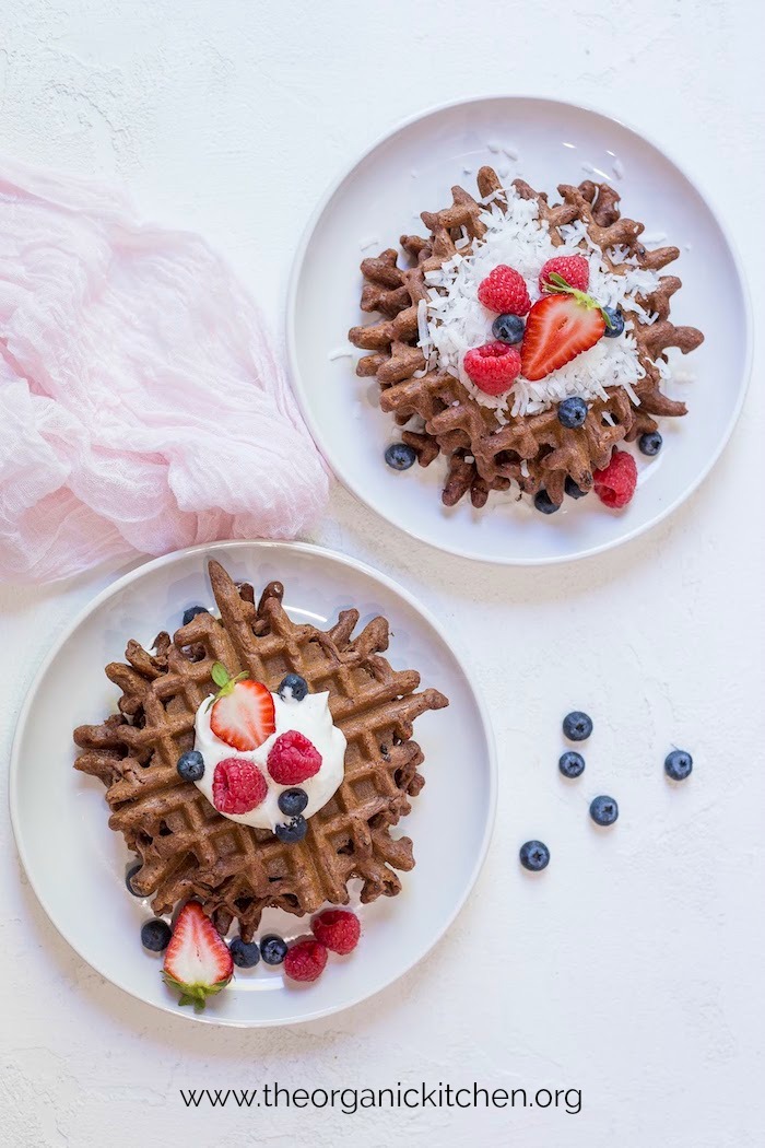 Two plates of Easy Chocolate Waffles with Paleo-Grain Free Option on white backdrop with light pink cloth