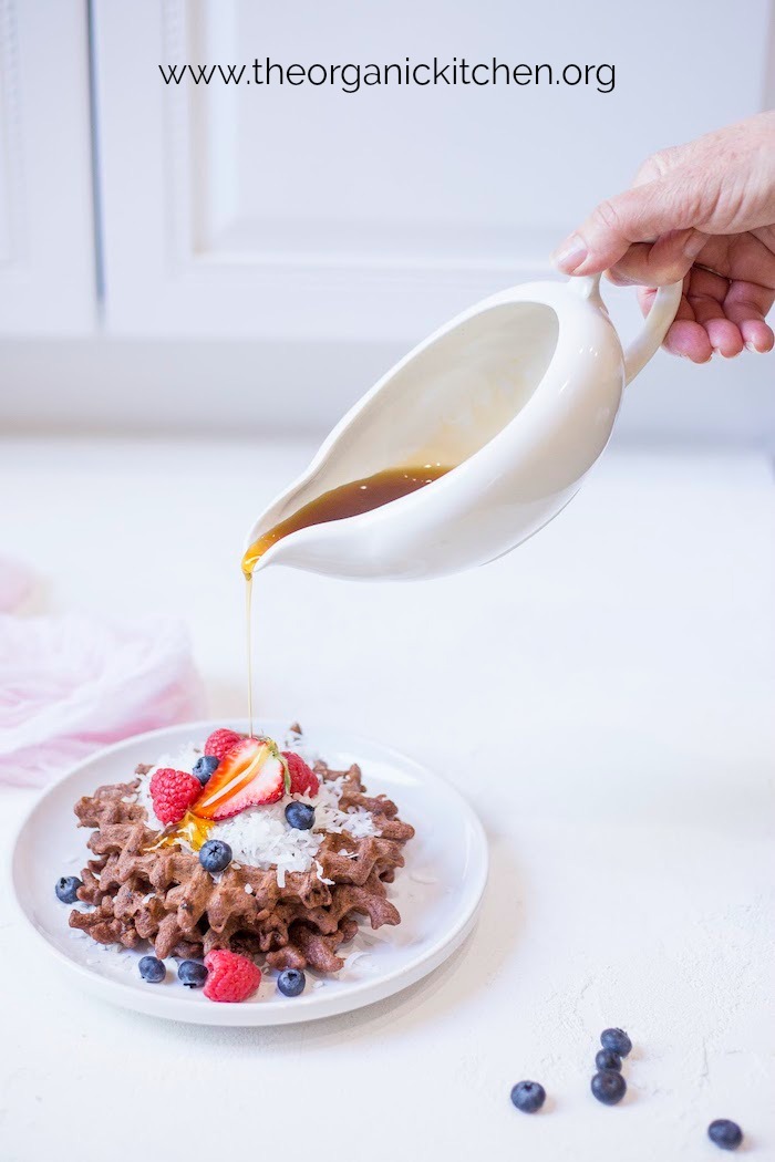 A woman pouring syrup on Easy Chocolate Waffles with Paleo-Grain Free Option 