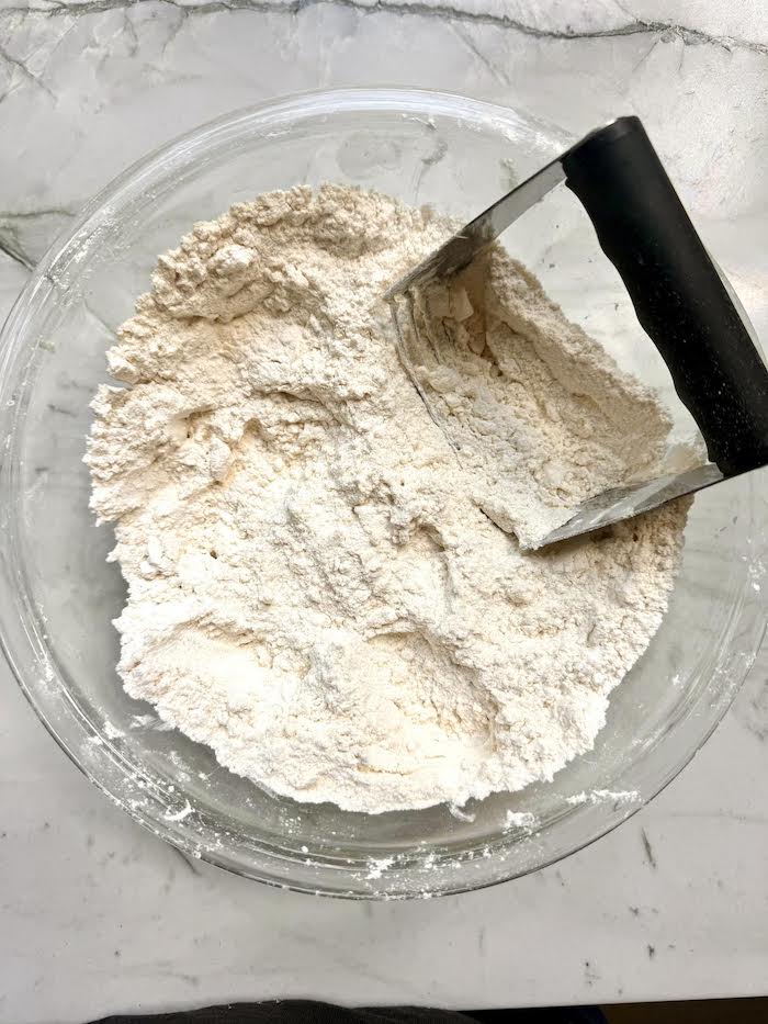 Dough in a glass bowl with a pastry cutter
