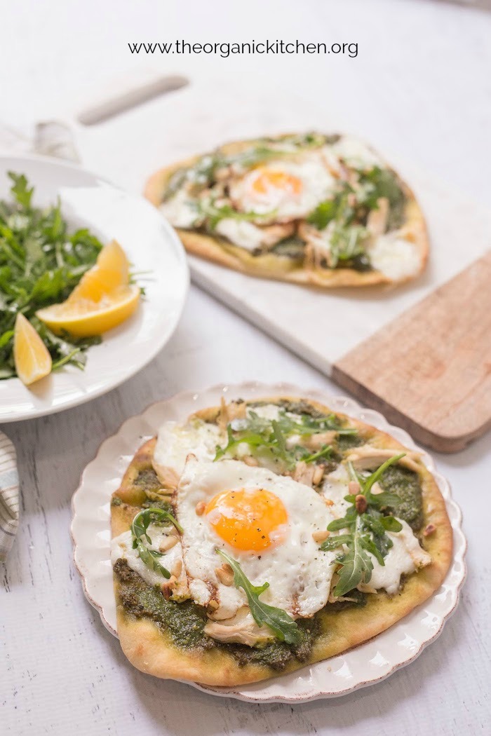 Two Chicken Pesto Burrata Naan Pizzas with Fried Egg on white plate and platter