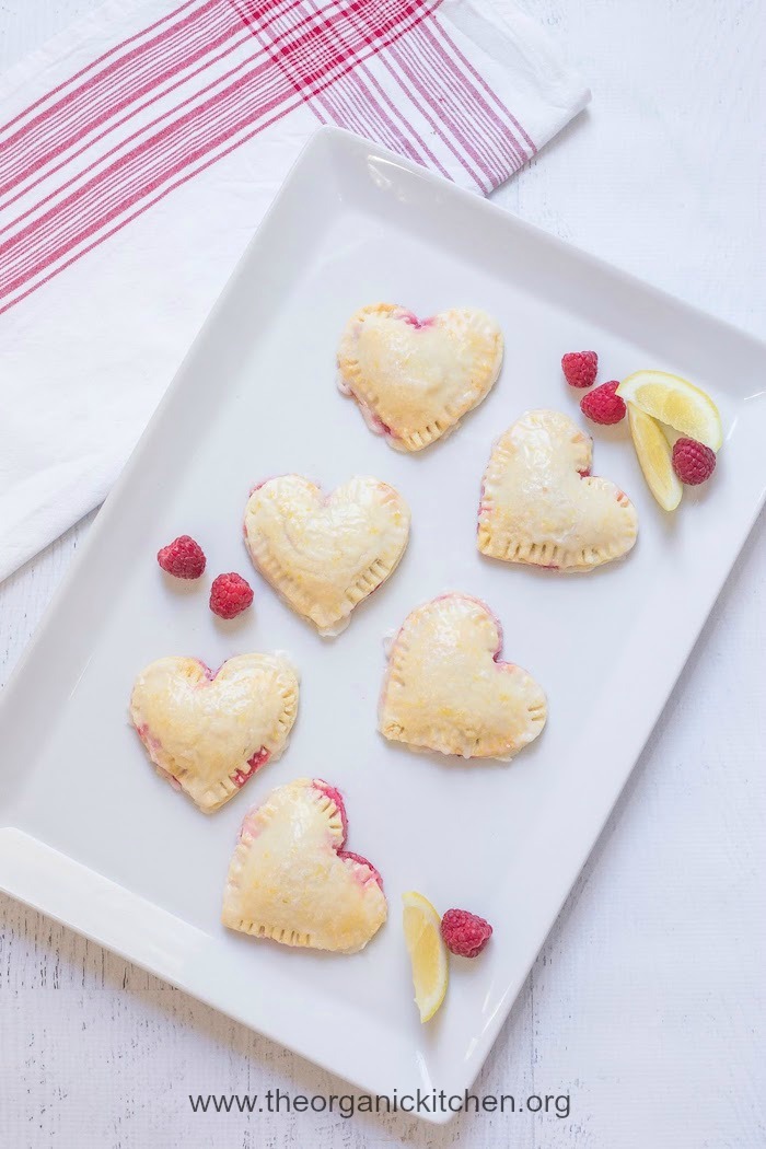 Six Raspberry-Lemon Hand Pies on white platter with red and white dish cloth