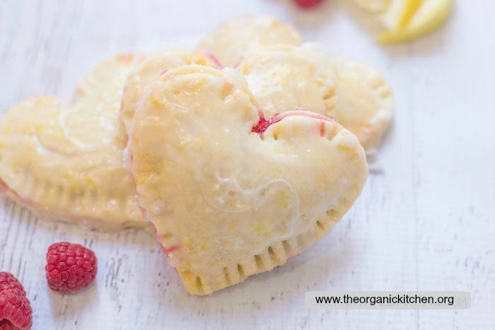 Three heart shaped Raspberry-Lemon Hand Pies on white wood