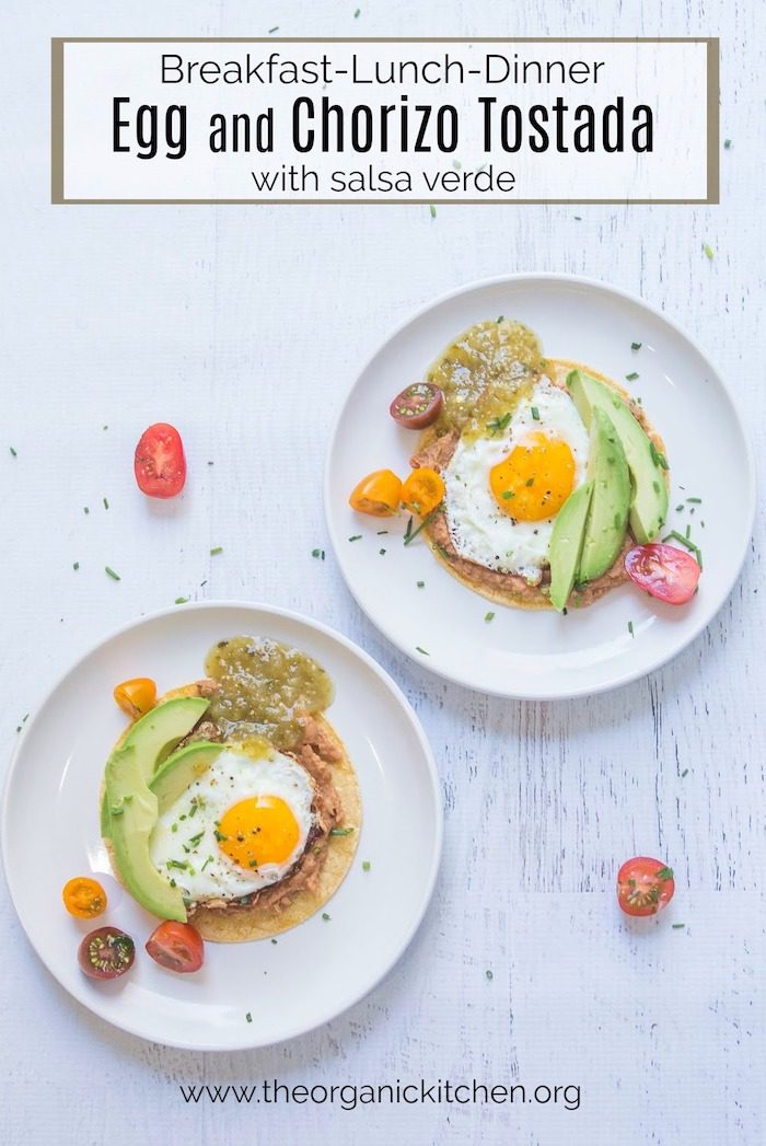 Egg, Bean and Chorizo Tostada with Salsa Verde Two plates of Egg, Bean and Chorizo Tostada with Salsa Verde on white wood surface